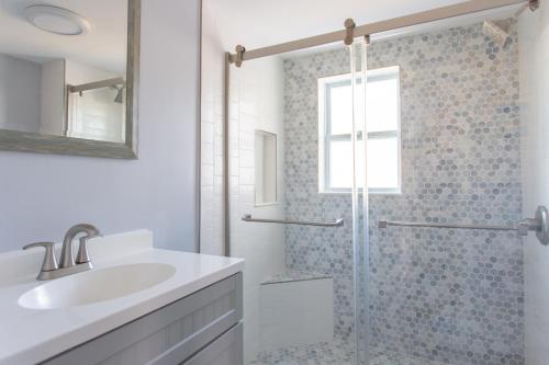 a white bathroom with a shower and a sink at Cozy 2 Bedroom Home Minutes from Beach & Bars in Jacksonville Beach