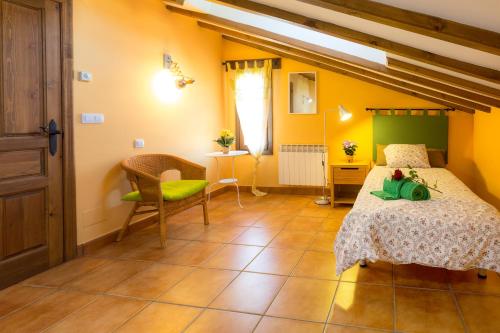 1 dormitorio con paredes amarillas, 1 cama y 1 silla en Casa Fresneda, en Fresneda de la Sierra Tirón