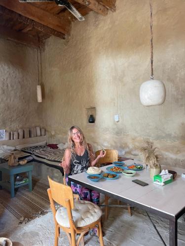 a woman sitting at a table with a plate of food at Baben Home in Siwa