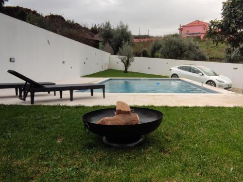 a barbecue in the grass next to a pool at Pomar das Oliveiras - Private Swimming pool - Free EV Chrg - Pet Friendly in Carvalhal Cimeiro