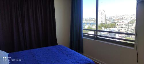 a bedroom with a blue bed and a large window at Vista Mar Loft Apartment Downtown Valparaíso in Valparaíso