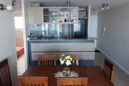 a kitchen with a wooden table and a dining room at Depto. frente a la playa con hermosa vista al mar y faro La Serena in La Serena