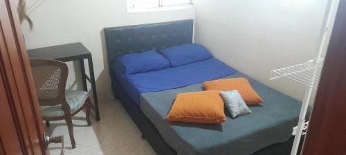 1 cama con 2 almohadas y 1 silla en una habitación en Alcobas con desayuno incluido baño compartido, en Medellín