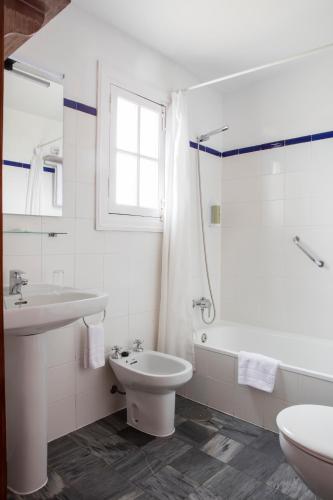 a white bathroom with a sink and a toilet at Hotel Tugasa Convento San Francisco in Vejer de la Frontera