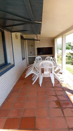 un patio con sillas blancas y una mesa en el porche en Casa a media cuadra de la playa, en La Paloma
