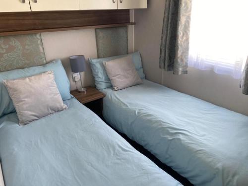 two beds sitting next to each other in a bedroom at CP1 Caravan, Howelston Holiday Park in Haverfordwest