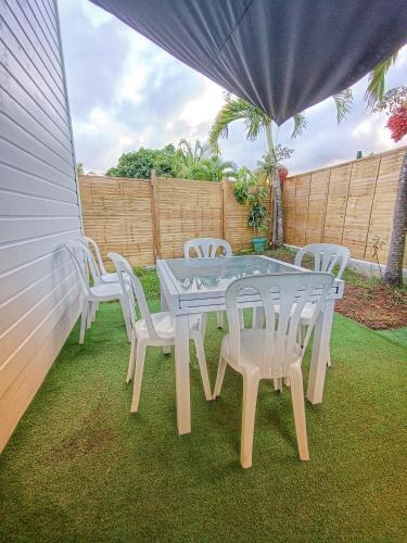 a white table and four white chairs on a lawn at Bungalow Bois Détente in Capesterre-Belle-Eau