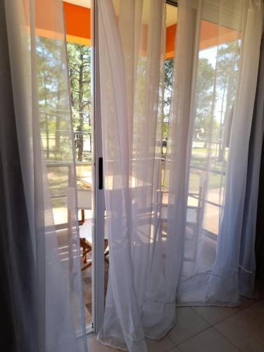 una puerta corredera de cristal con cortinas blancas en una habitación en Los Ranchos Termas en Colón