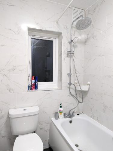 a white bathroom with a toilet and a bath tub at The Saxon Rooms in Barking