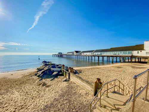 a beach with a pier and the ocean at Sea Mouse Cottage in Southwold