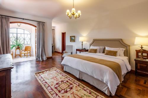 um quarto com uma cama grande e um lustre em Pousada Vila Alto dos Pinhais em Espírito Santo do Pinhal