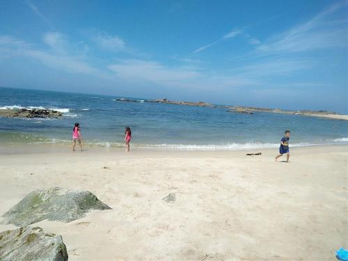 three children playing on a beach with the ocean at Casa Alba in Mindelo