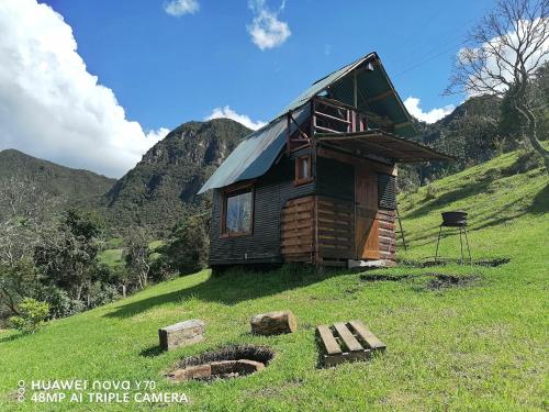una pequeña casa de madera en una colina en un campo en casita en la montaña, cabañas paraíso, en Sesquilé
