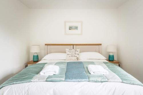 a bed with two towels and two lamps on it at The Coach House at Lower Coombe Royal- Family/Dogs in Kingsbridge