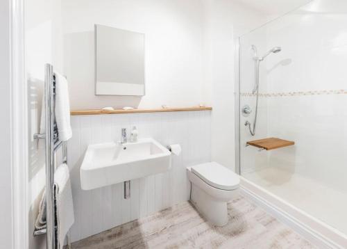 biała łazienka z toaletą i umywalką w obiekcie The Coach House at Lower Coombe Royal- Family/Dogs w mieście Kingsbridge
