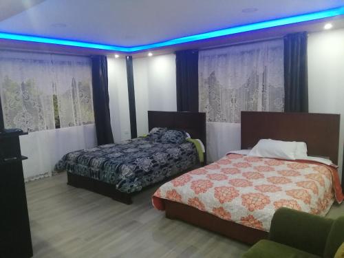 1 dormitorio con 2 camas y luz azul en Casa de Campo El Cabañal, en Quito