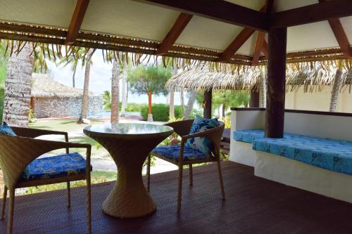 Habitación con porche con mesa y sillas. en Tamanu Beach, en Arutanga