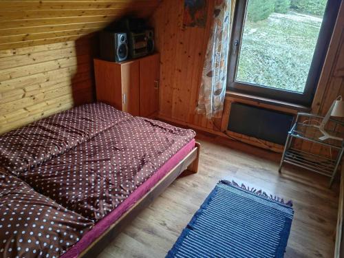 a small bed in a room with a window at Chata Stella in Mengusovce