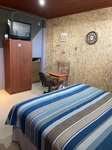Schlafzimmer mit einem Bett, einem Schreibtisch und einem TV in der Unterkunft HuehueLoft1 estacionamiento y wifi in Huehuetenango