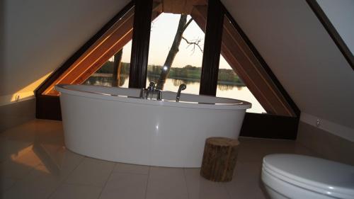 a bathroom with a bath tub in front of a window at Rybacka Osada in Piecki