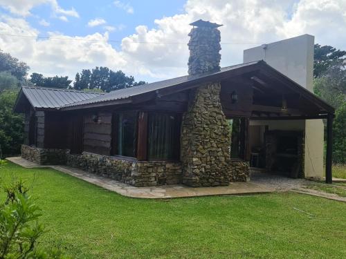 una casa de piedra con una chimenea a un lado en Cabaña en los Acantilados en Mar del Plata