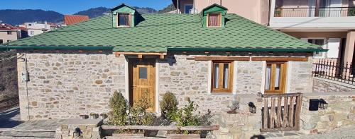 a small stone house with a green roof at The House in the Cobbled Road in Karpenision