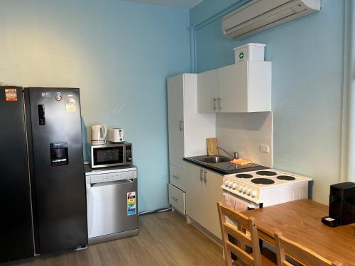 a small kitchen with a black refrigerator and a table at Comfortable 1 bedroom duplex close to everything in Budgewoi