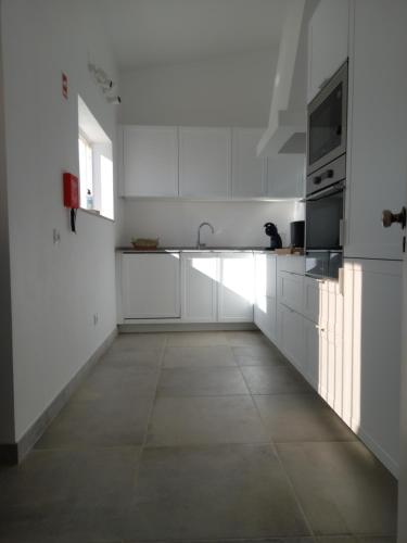 a white kitchen with white cabinets and a sink at Tasi Ingrina in Vila do Bispo