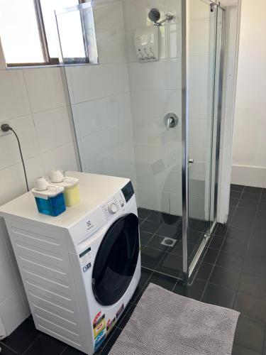 a washing machine in a bathroom with a shower at Comfortable 1 bedroom duplex close to everything in Budgewoi