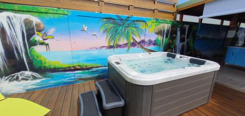 a bathroom with a tub with a painting on the wall at "Chez Claudia "charmant logement avec jacuzzi privatif en toute intimité sur belle terrasse extérieure en bois et piscine in Courcelles Sucrerie
