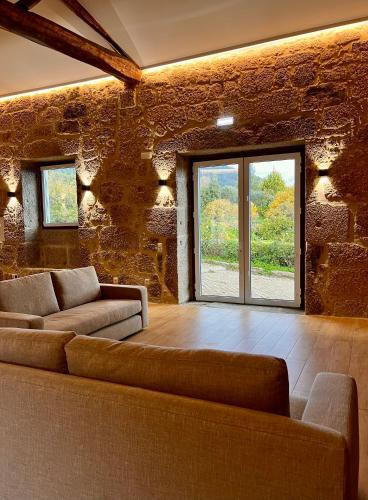 a living room with two couches and a stone wall at Quinta da Porta - Solar de Vale de Prazeres in Vale de Prazeres