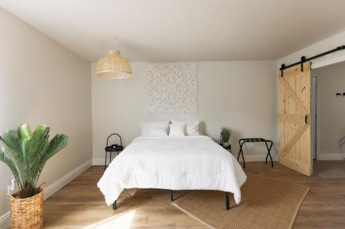 a bedroom with a white bed and a potted plant at Minutes to JT National Park, Hot Tub & Game Room in Joshua Tree