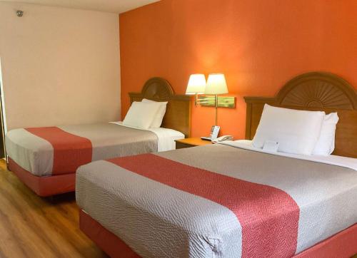 two beds in a hotel room with orange walls at Motel 6-Normal, IL - Bloomington Area in Cardinal Court
