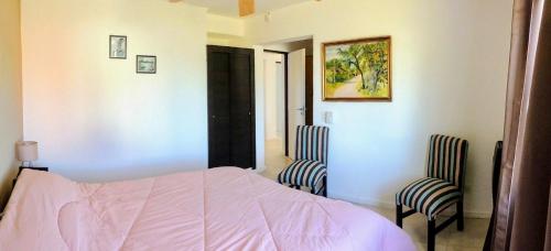um quarto com uma cama e 2 cadeiras em Chalet Kuyen III em Las Grutas