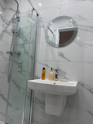 a white bathroom with a sink and a mirror at JJ Serviced Apartment - Close to Tube Station & Near Central London & Wembley in Northolt