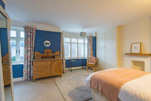 Schlafzimmer mit einem Bett, einer Kommode und Fenstern in der Unterkunft Prospect Cottage by Bloom Stays in Hythe