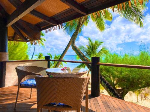 a table and chairs on a deck with a view of the ocean at Tamanu Beach in Arutanga