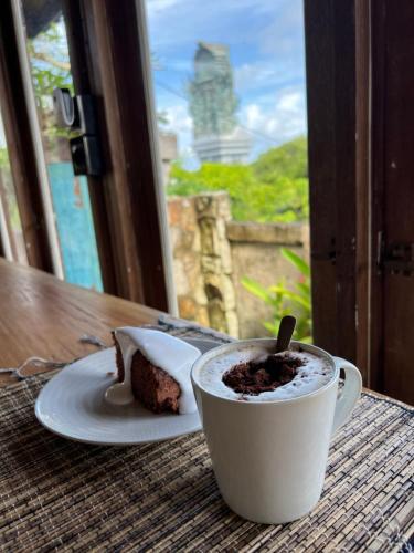 a cup of coffee and a piece of cake on a table at PINOKKIO B&B Restaurant in Jimbaran