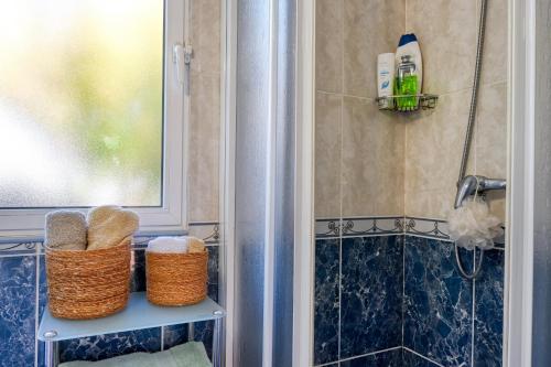 a bathroom with two baskets on a shelf next to a shower at Casa do Pinheiro, a Home in Madeira in São Vicente