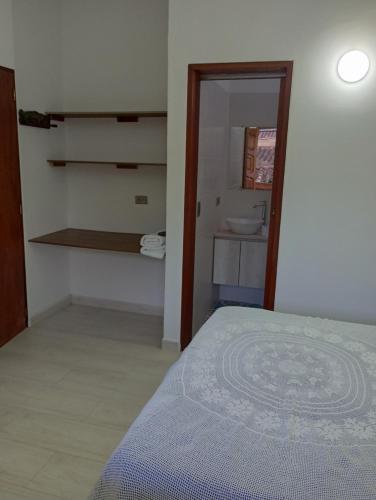 a bedroom with a bed and a bathroom with a sink at Hostal Famihotel Fundadores in Jardin