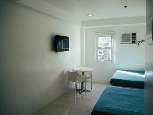 a room with two beds and a table and a window at Wanderlust Bed & Breakfast in Puerto Princesa City