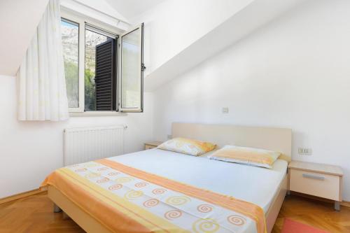 a white bedroom with a bed and a window at Apartments with a parking space Dugi Rat, Omis - 11443 in Dugi Rat