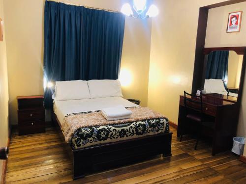 1 dormitorio con 1 cama con cortina azul y espejo en Hostal casa franciscana, en Quito