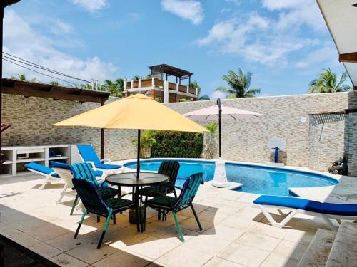 un patio con mesa, sillas y piscina en Casa en el puerto frente al mar!, en Puerto San José