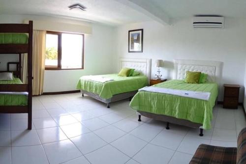 a bedroom with two beds with green sheets at Casa en el puerto frente al mar! in San José de Guatemala