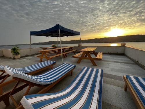 a deck with picnic tables and chairs and an umbrella at Noprea Boutique Hotel in Aswan