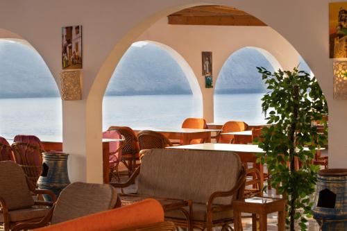 a restaurant with arched windows and tables and chairs at Noprea Boutique Hotel in Aswan