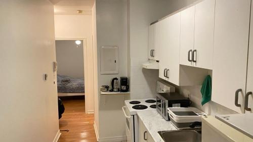 a white kitchen with a sink and a stove at The Parkdale Hostellerie in Toronto