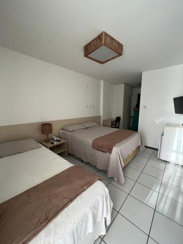 um quarto de hotel com duas camas e uma televisão em Flat no Resort Gran Lençóis em Barreirinhas