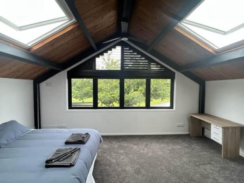 ein Schlafzimmer mit einem Bett und einem großen Fenster in der Unterkunft The clubhouse in Hamilton